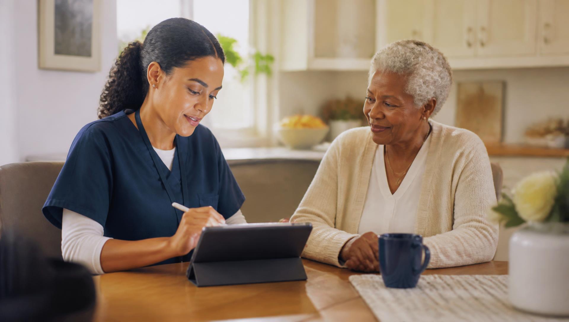 Home health nurse documenting a visit on a tablet at a senior client's kitchen table